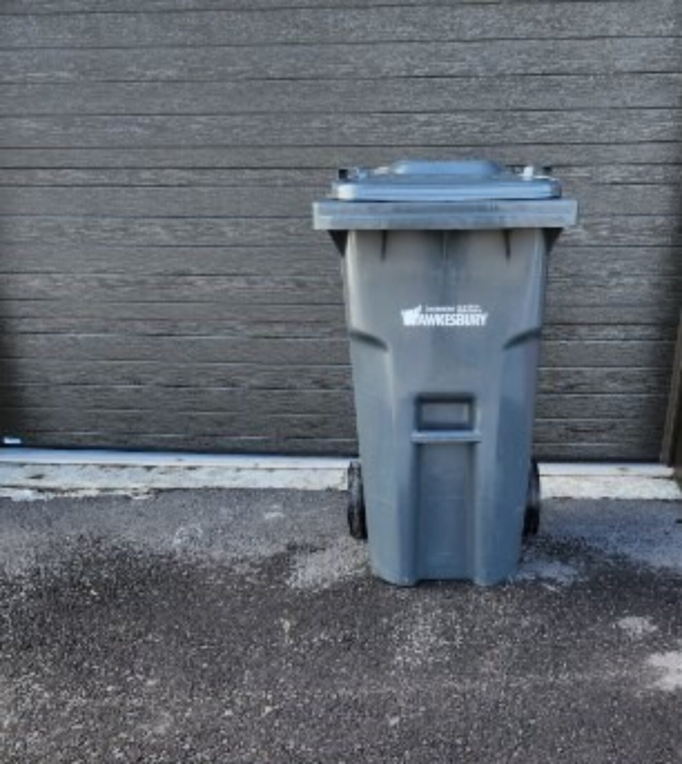 Poubelle à roulettes grise avec le logo de la Ville en blanc sur le devant.