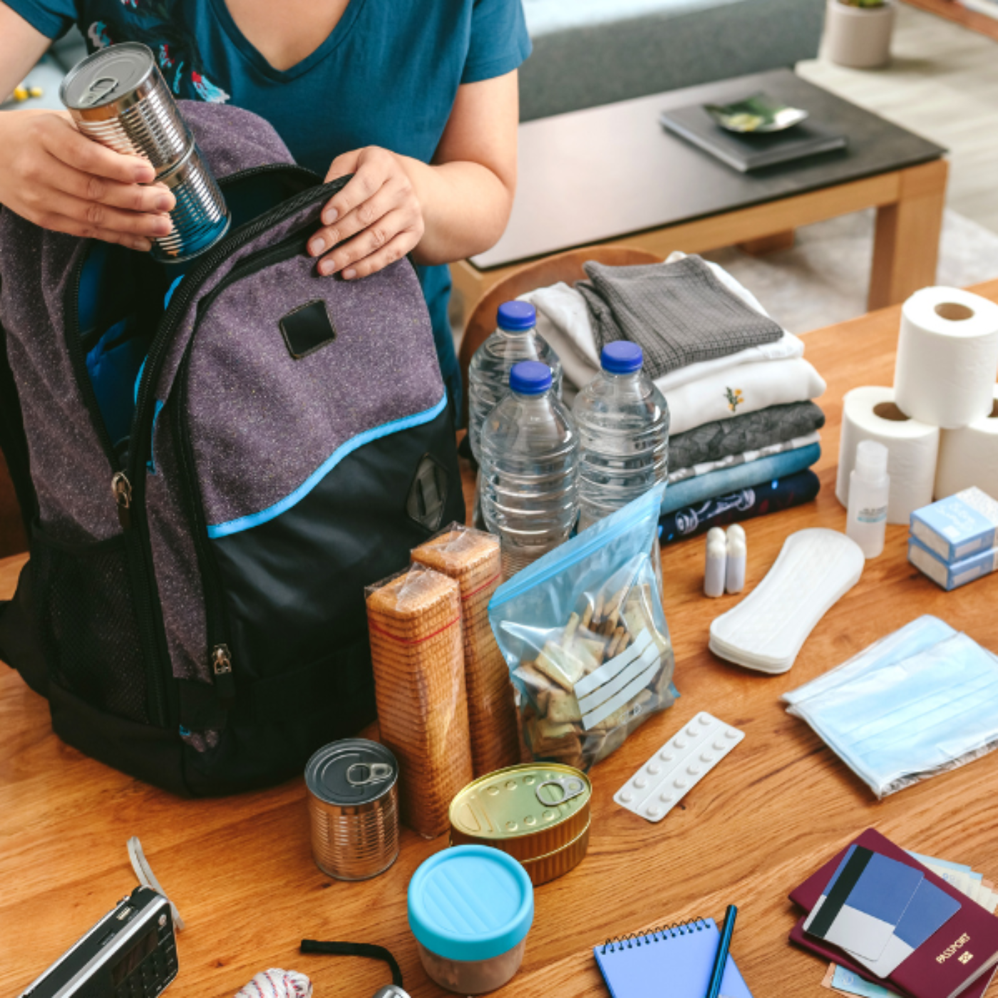 Generic photo of a person putting non-perishable items in a backpack.