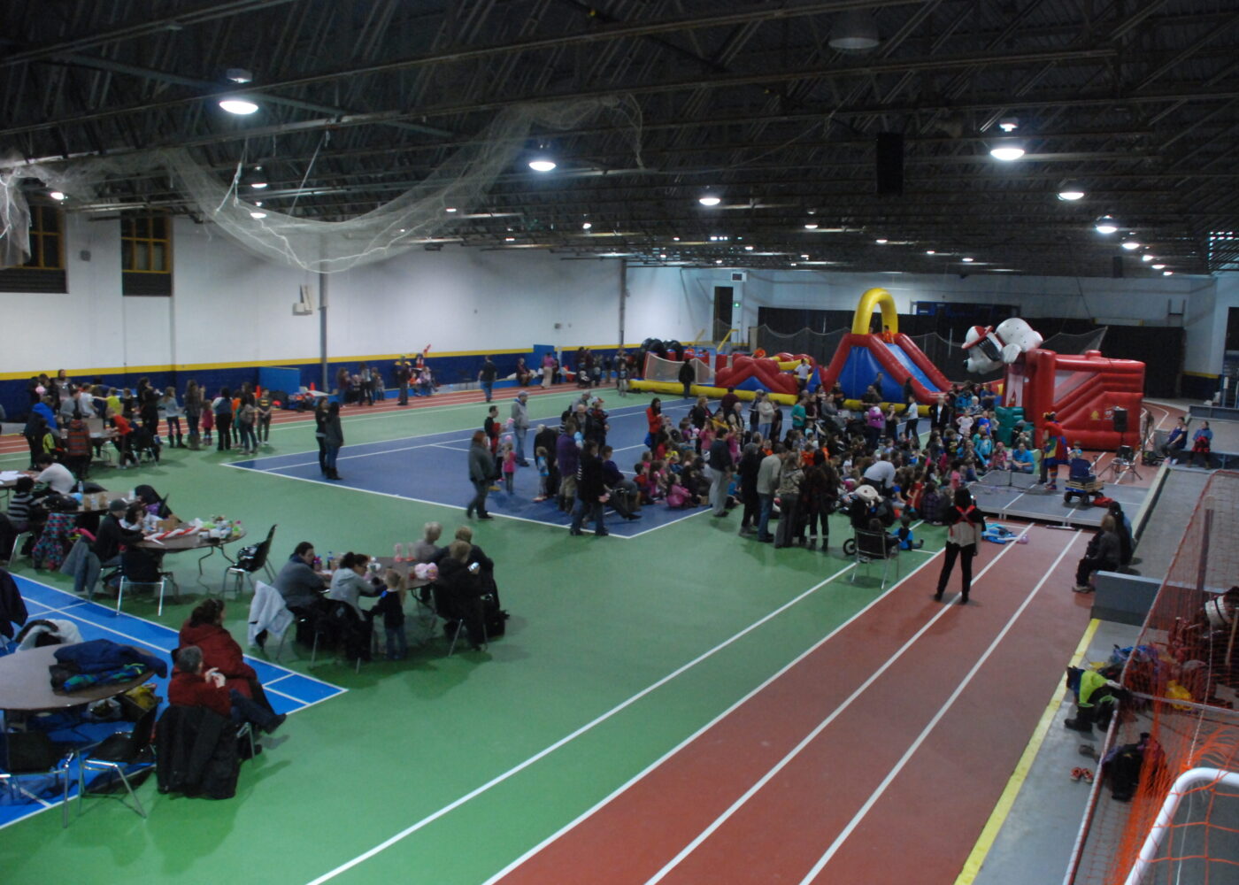 Photo of the sports complex's multi-sports hall used to celebrate an event with inflatable games, tables and several people.
