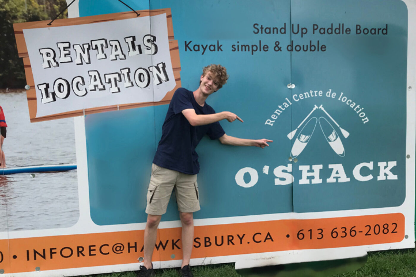 Photo of a person in front of an advertisement for the O'Shack kayak rental center.