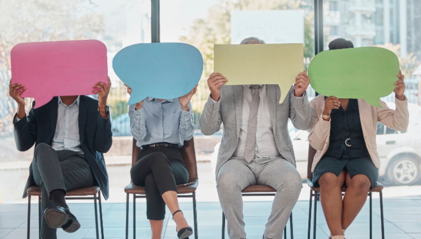 Generic image of 4 people sitting on chairs. One with a pink speech bubble cutout, the other with a blue one, the third with a yellow one and the last with a green one.