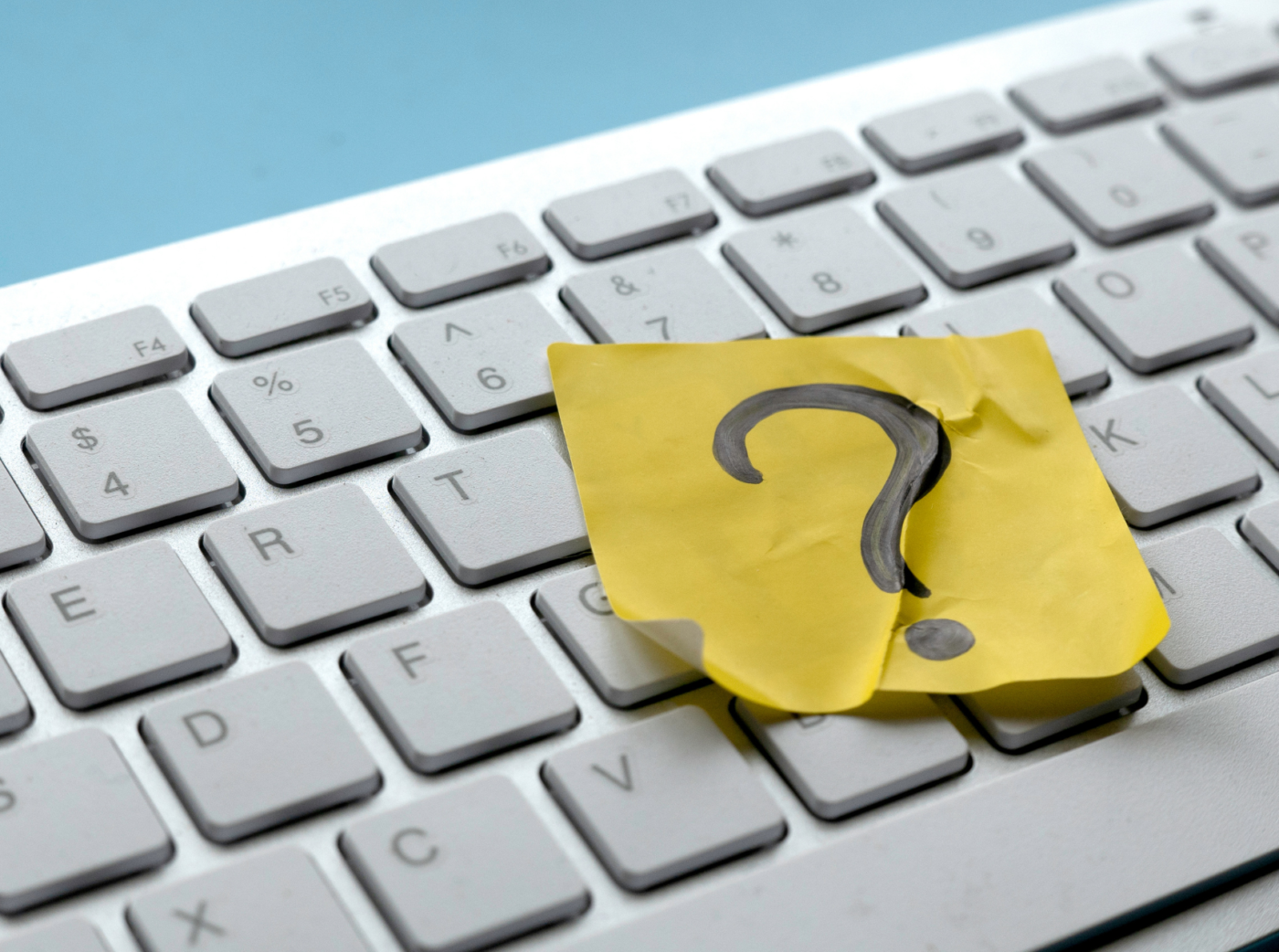 Generic image of a computer keyboard with a yellow post-it note bearing a question mark.