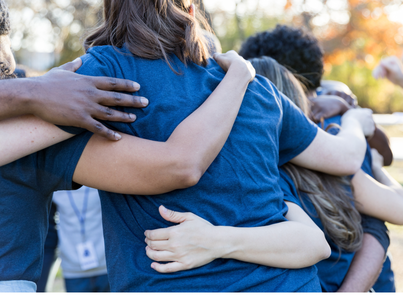 Photo of a lot of people standing in a circle arm in arm