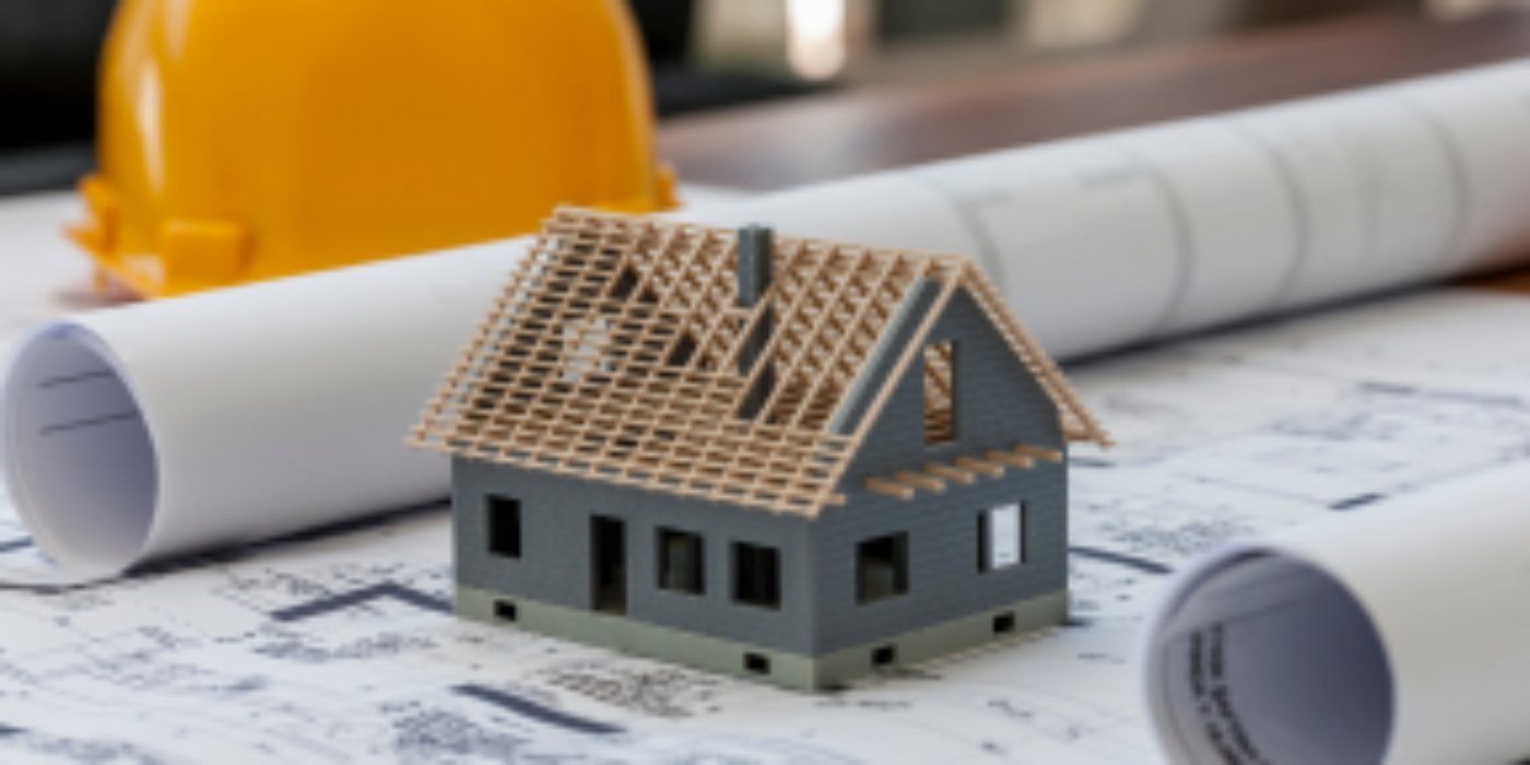 Generic image of a small toy house under construction on building plans