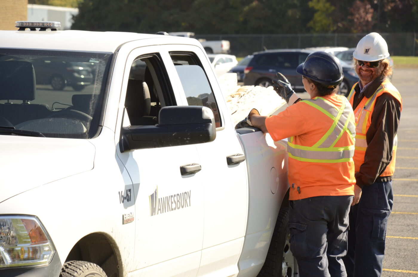 Photo of Town of Hawkesbury employees wearing safety vests and standing next to a Town vehicle.
