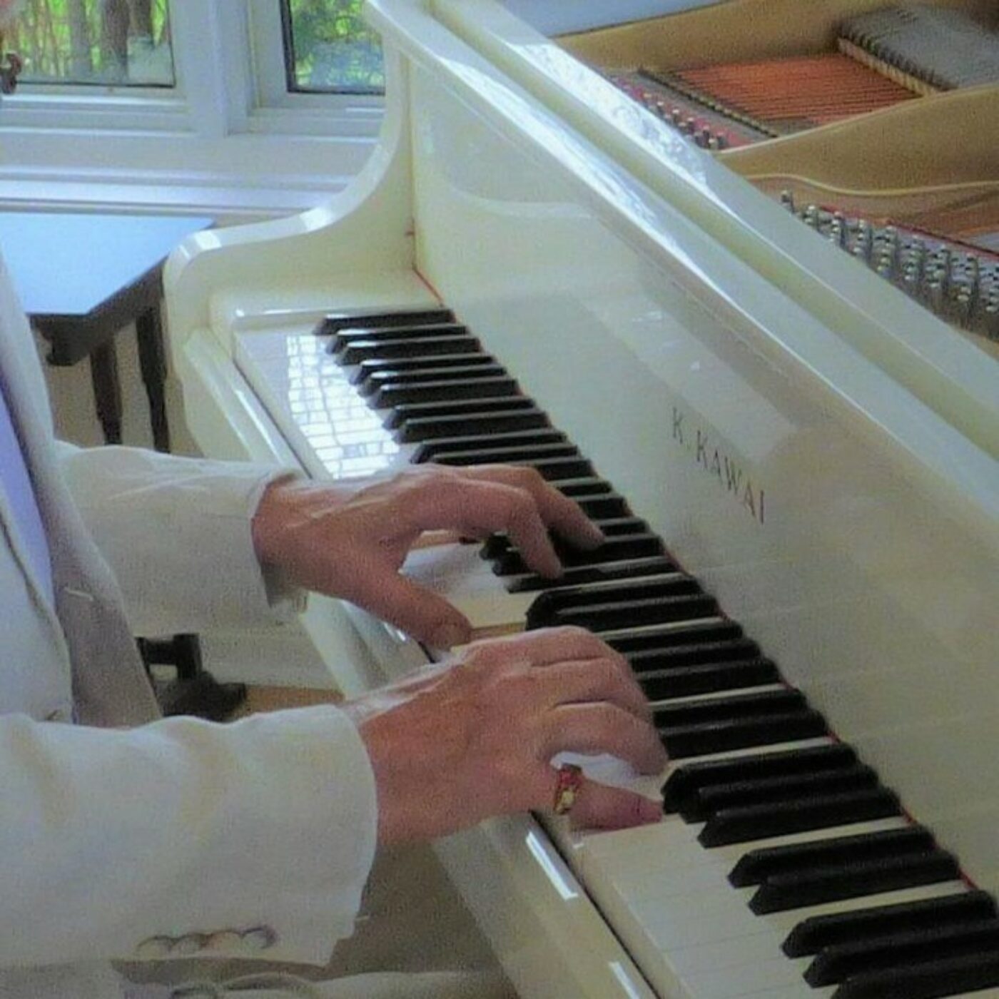 Close-up of a person dressed in a white suit playing the piano.