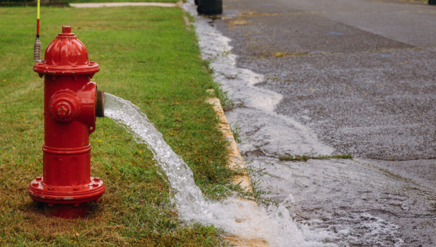 Photo d'une borne-fontaine dont de l'eau s'écoule vers la rue
